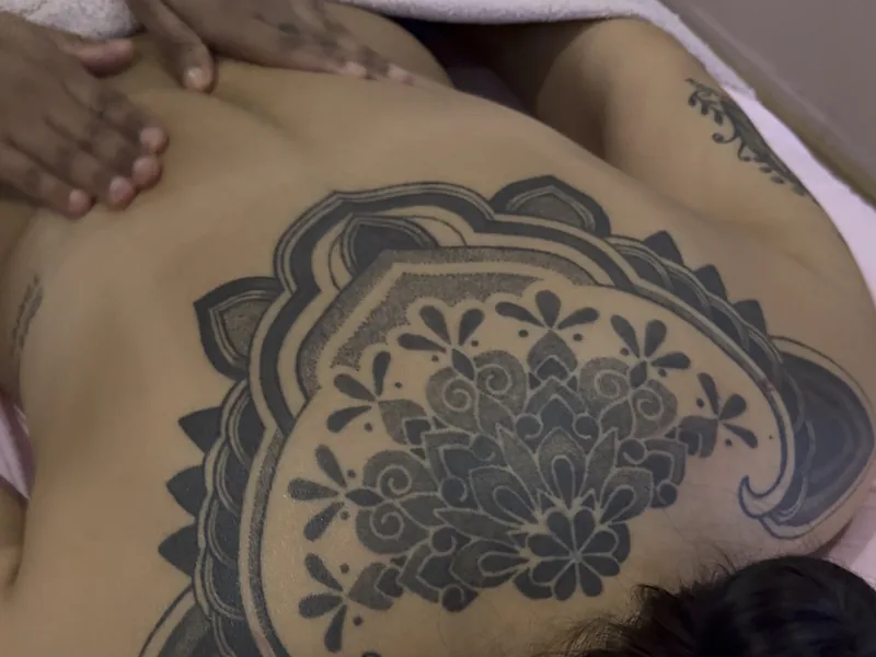Handen van een masseuse op de rug van een vrouw op de behandeltafel